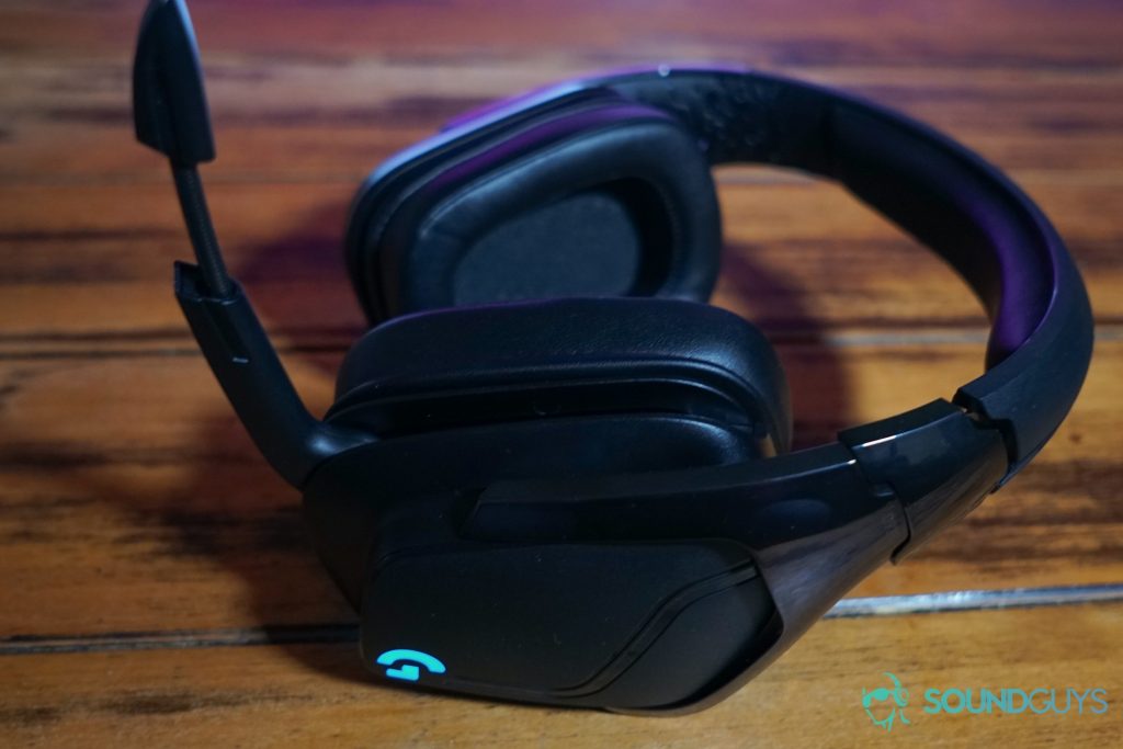 The Logitech G935 sits on a wooden table bathed in the pink glow of a TV screen