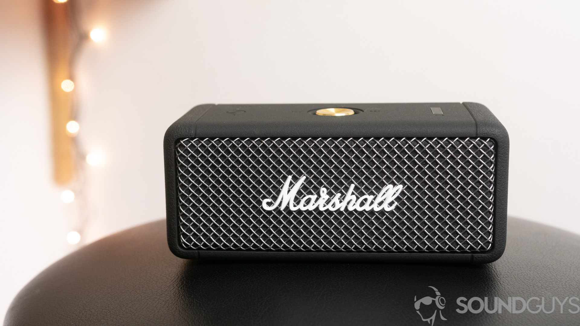 Marshall Emberton Bluetooth speaker on a black stool with lights in the background