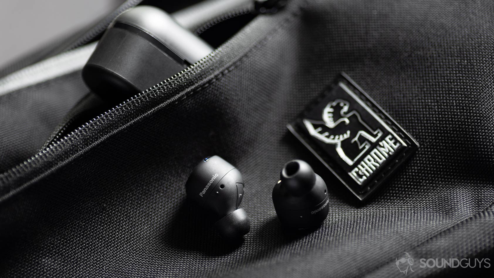 A picture of the Panasonic RZ-S500W noise canceling earbuds on a Chrome sling bag with the case angled in the zippered pocket of the bag.