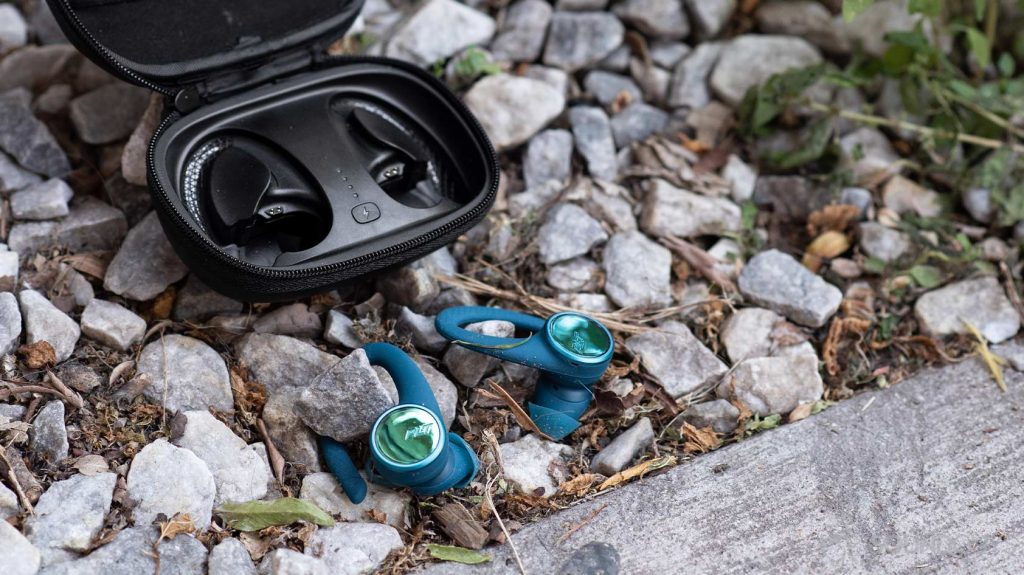 A picture of the Plantronics BackBeat FIT 3200-true wireless workout earbuds on a pebbled surface in front of the charging case.
