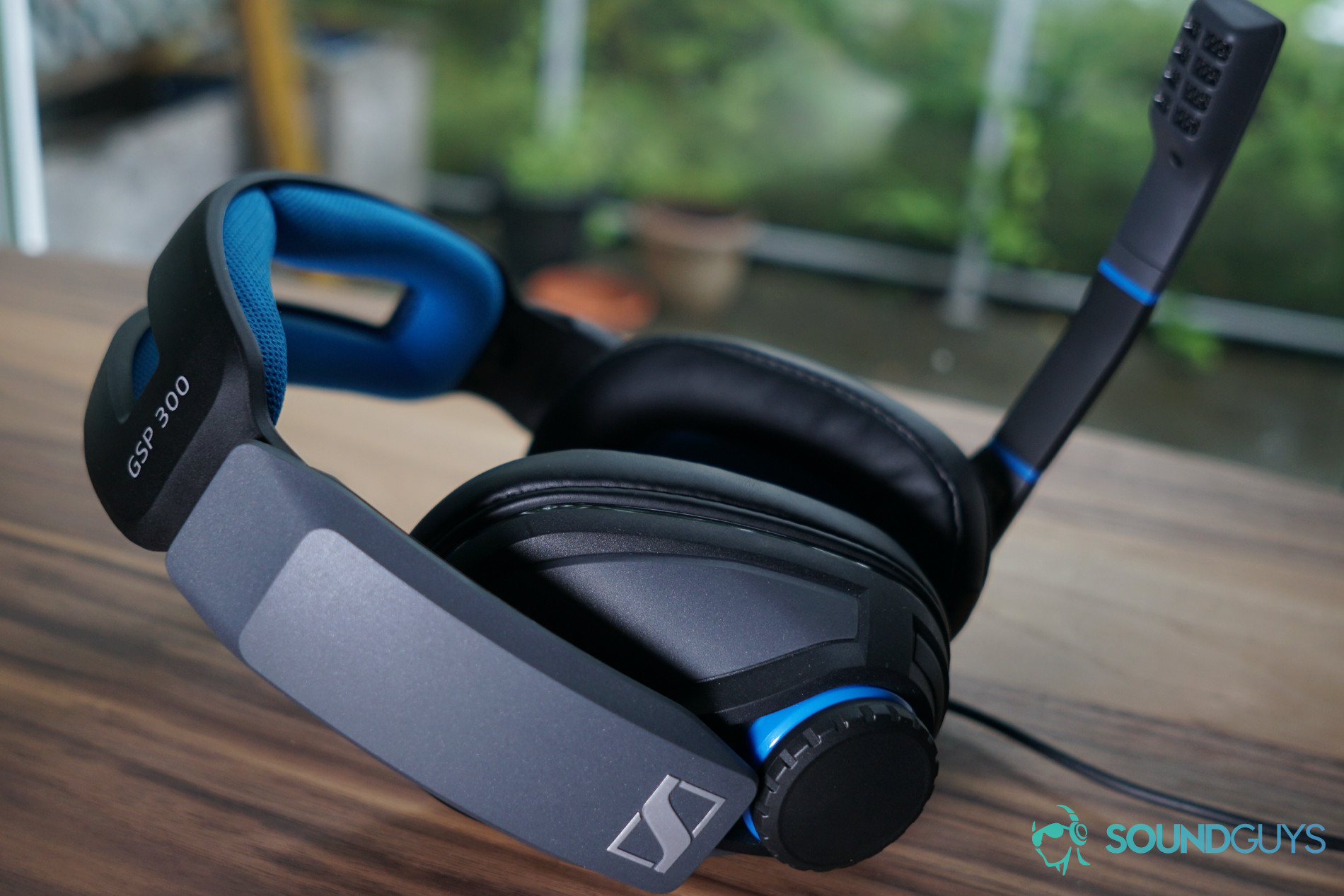 The Sennheiser GSP 300 gaming headset lays on a wooden table by a window.