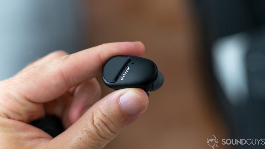 Man holding a single Sony WF-SP800N true wireless earbud in hand