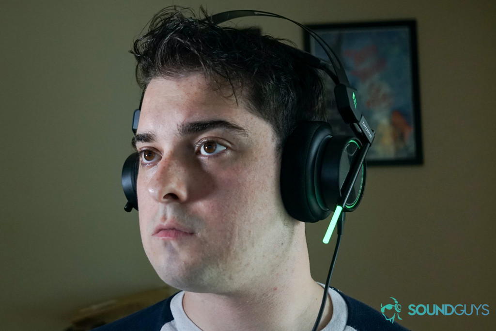 A man wears the 1More Spearhead VR sitting at a PC with a My Brother, My Brother, and Me poster behind him.