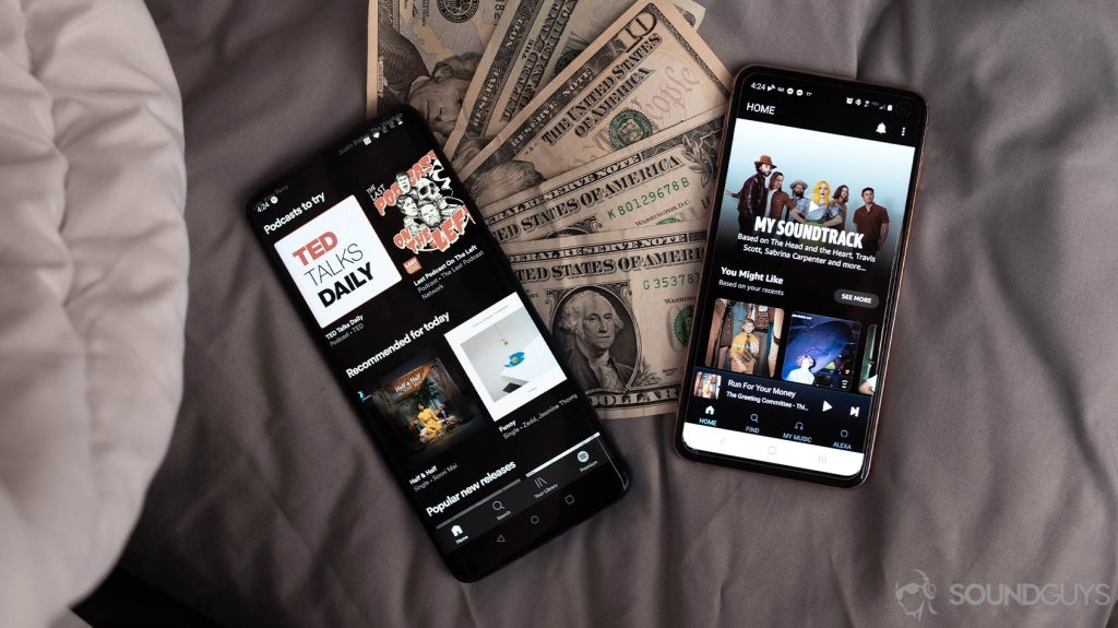 An aerial image of Spotify Premium vs Amazon Music HD on two smartphones laid atop cash.