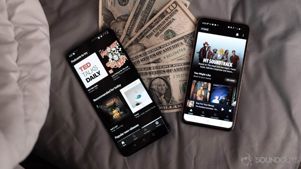 An aerial image of Spotify Premium vs Amazon Music HD on two smartphones laid atop cash to illustrate CD Baby payouts.
