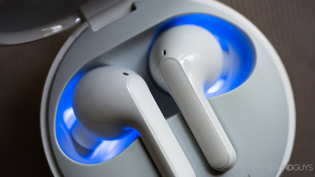 A close-up photo of the LG TONE Free HBS-FN6 true wireless earbuds in the UVnano charging case with the internal blue light on.