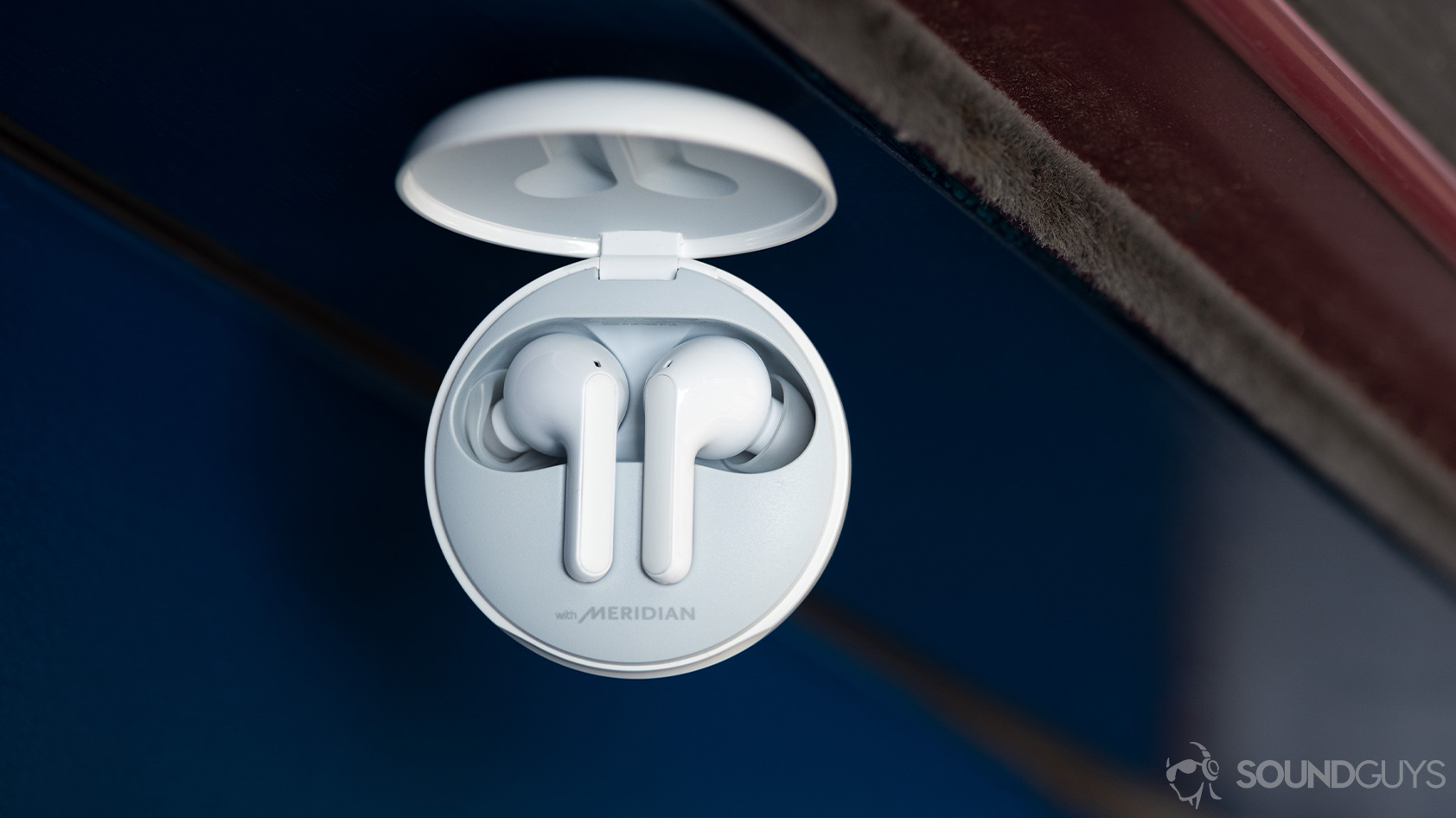 A close-up photo of the LG TONE Free HBS-FN6 true wireless earbuds in the open UVnano charging case with the Meridian logo on the inside.