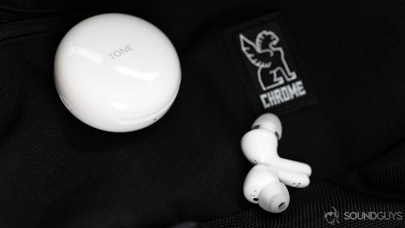 A photo of the LG TONE Free HBS-FN6-6 true wireless earbuds outside of the charging case showing the dedicated soft ear tips with the circular case in the background.