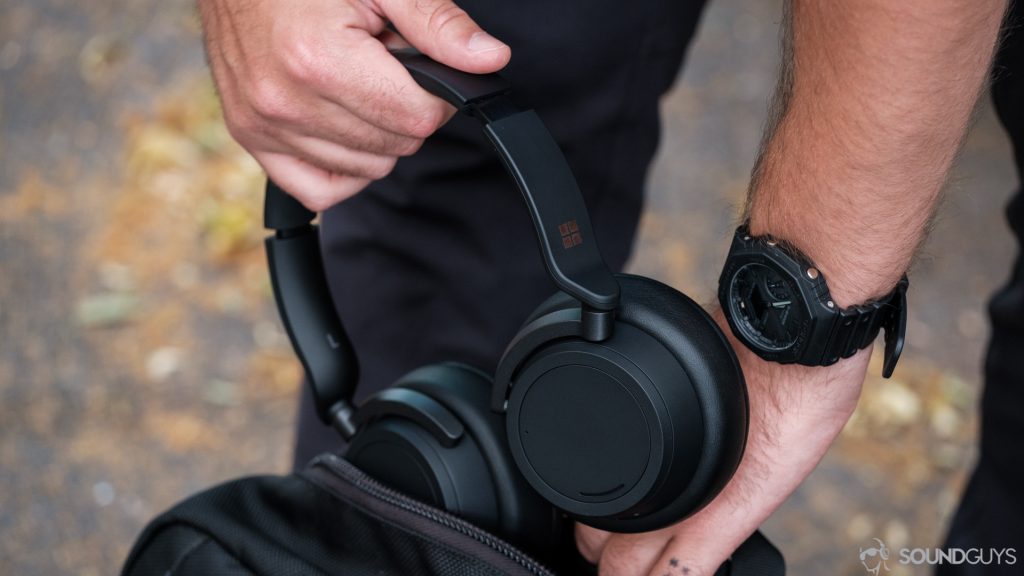 Photo of man putting the Microsoft Surface Headphones 2 in a backpack