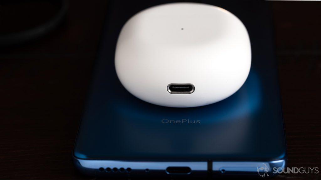 A picture of the OnePlus Buds true wireless earbuds charging case (USB-C port) on top of a OnePlus 7 smartphone (blue).