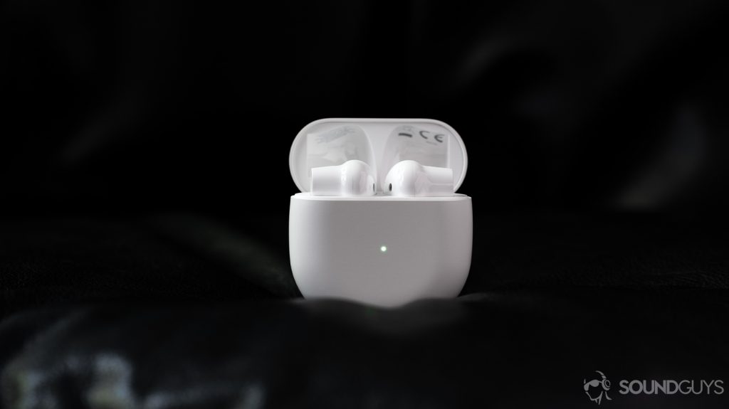 A picture of the OnePlus Buds true wireless earbuds (white) in the open charging case, which is standing erect against a black background.