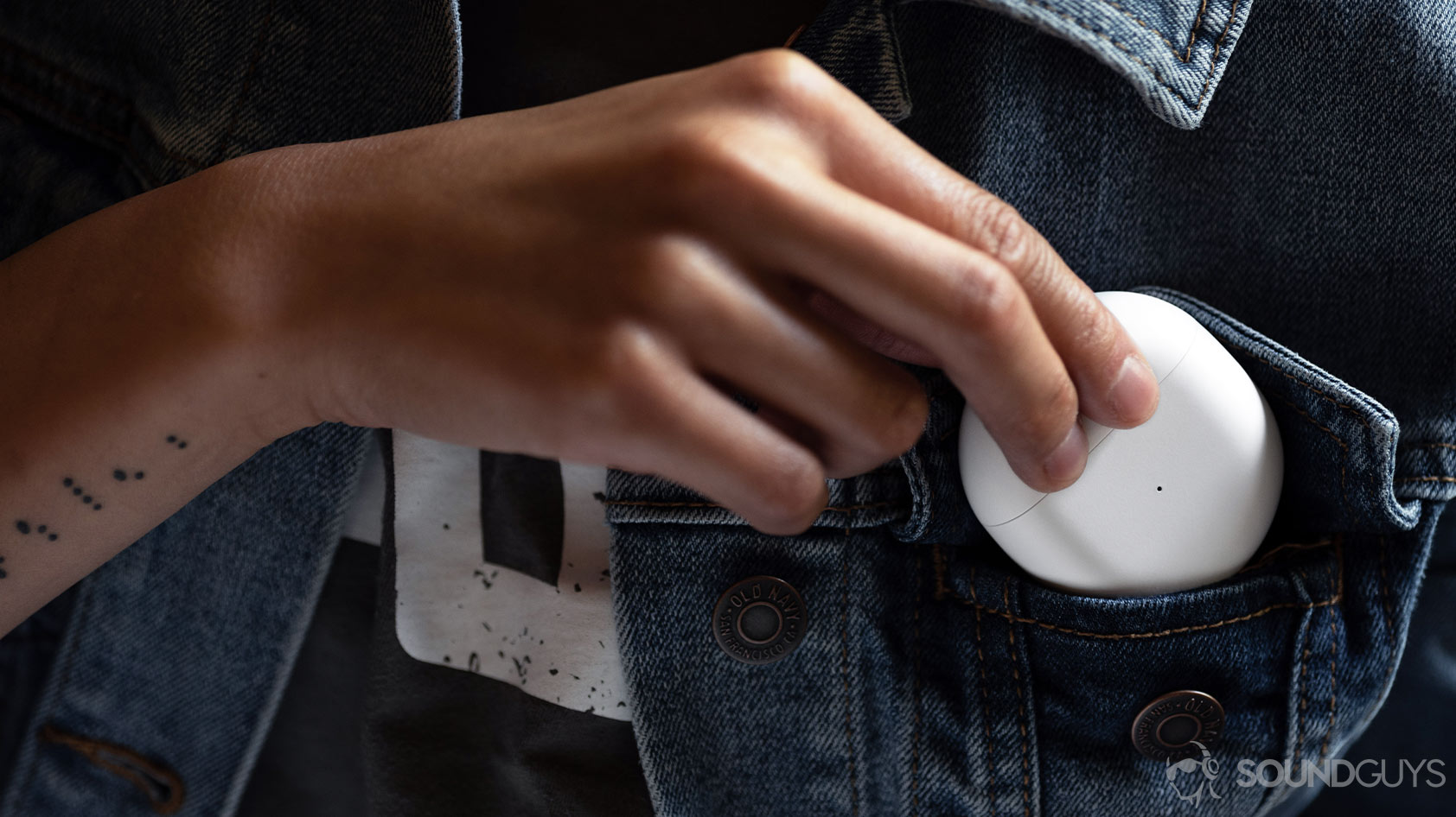 A picture of the OnePlus Buds true wireless earbuds case being inserted into the breast pocket of a denim jacket.