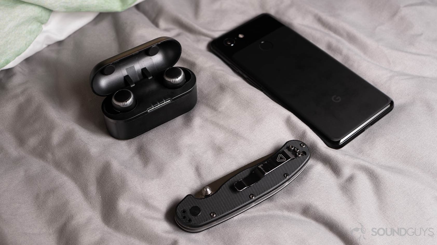 A photo of the Panasonic RZ-S300W true wireless earbuds next to a pocket knife and Google Pixel 3 smartphone.
