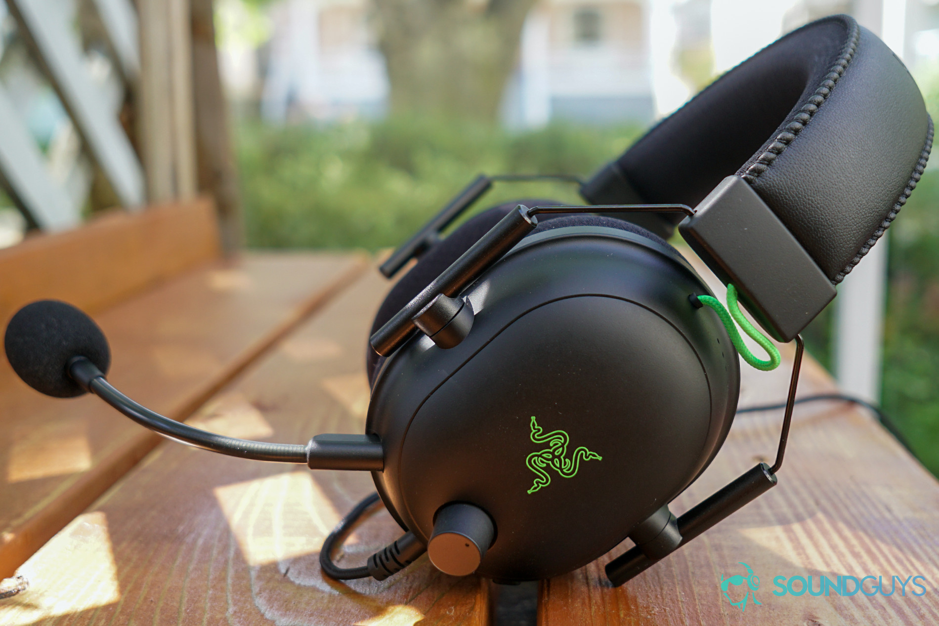 THe Razer BlackShark V2 gaming headset sits outside on a wooden table under a tree