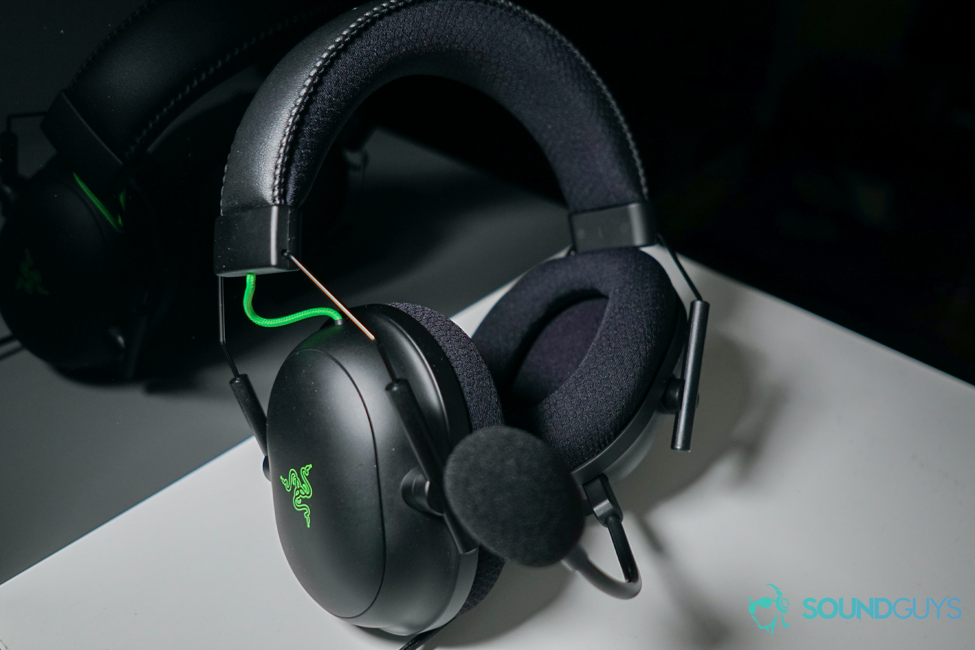The Razer BlackShark V2 gaming headset sits in a white box in front of a reflective black surface