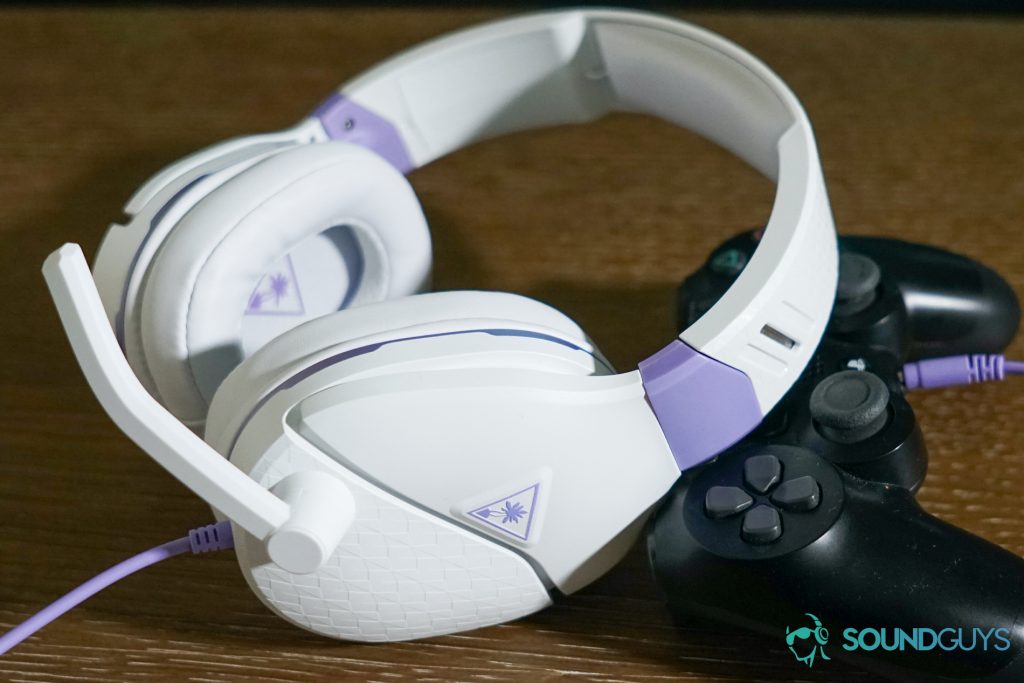The Turtle Beach Recon Spark gaming headset leans on a PlayStation DualShock 4 controller on a wooden table.