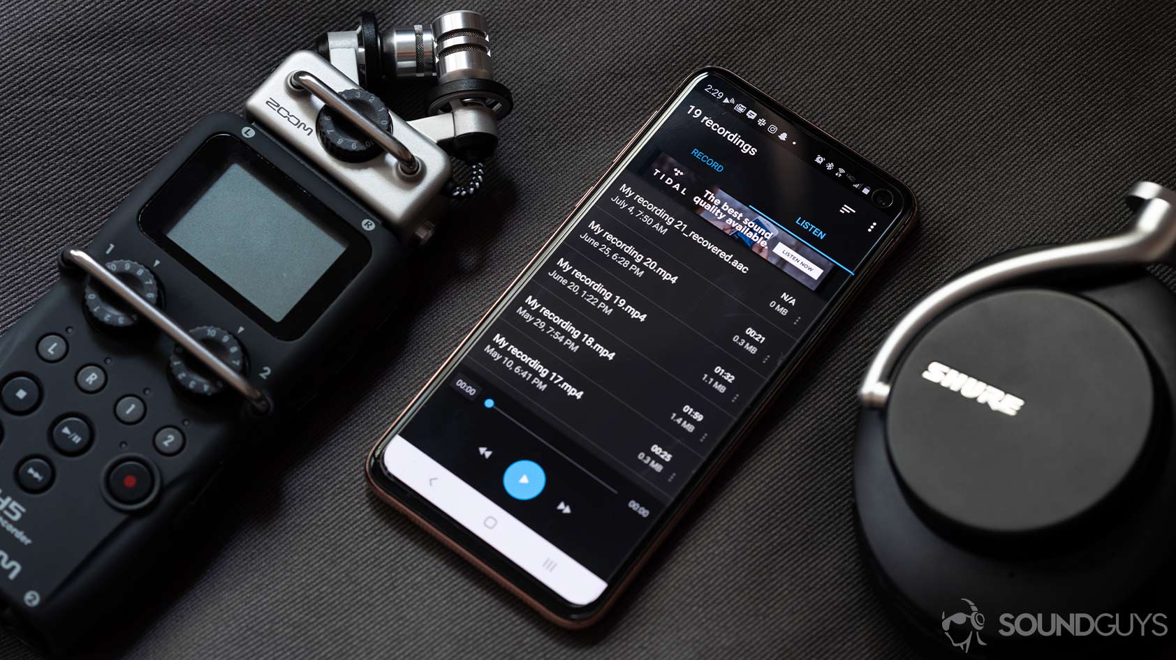 A picture of the Easy Voice Recorder app on a Samsung Galaxy S10e smartphone, flanked by a Zoom recorder and Shure noise canceling headphones.
