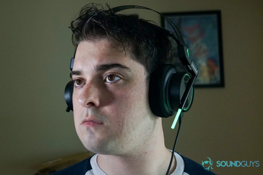 A man wears the 1More Spearhead VR sitting at a PC with a My Brother, My Brother, and Me poster behind him.