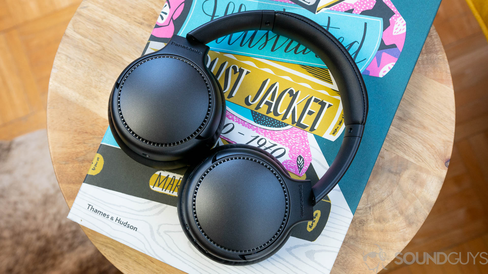 Pictured are the Panasonic RB-M700B headphones on a colorful book cover on wooden table