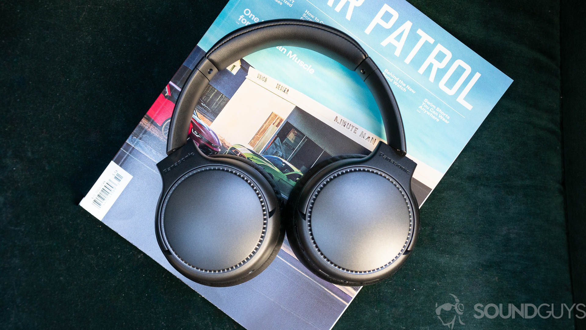 Pictured from above is the Panasonic RB-M700B headphones on top of a magazine on a green couch