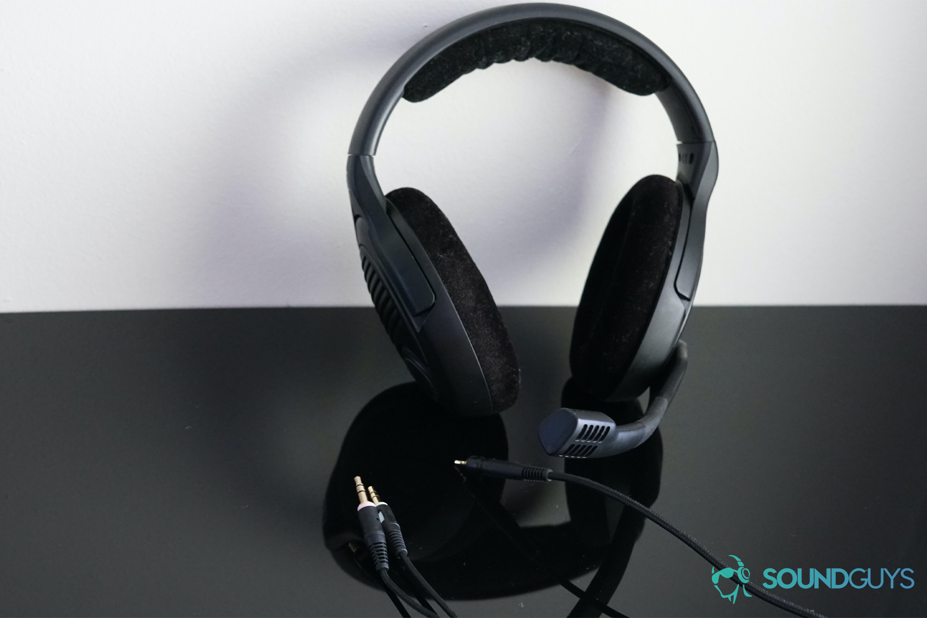 Sennheiser-PC37X-Out-of-the-box A picture of the Sennheiser PC37X leaned against a white wall on a reflective black surface with its detached audio cord in front of it.
