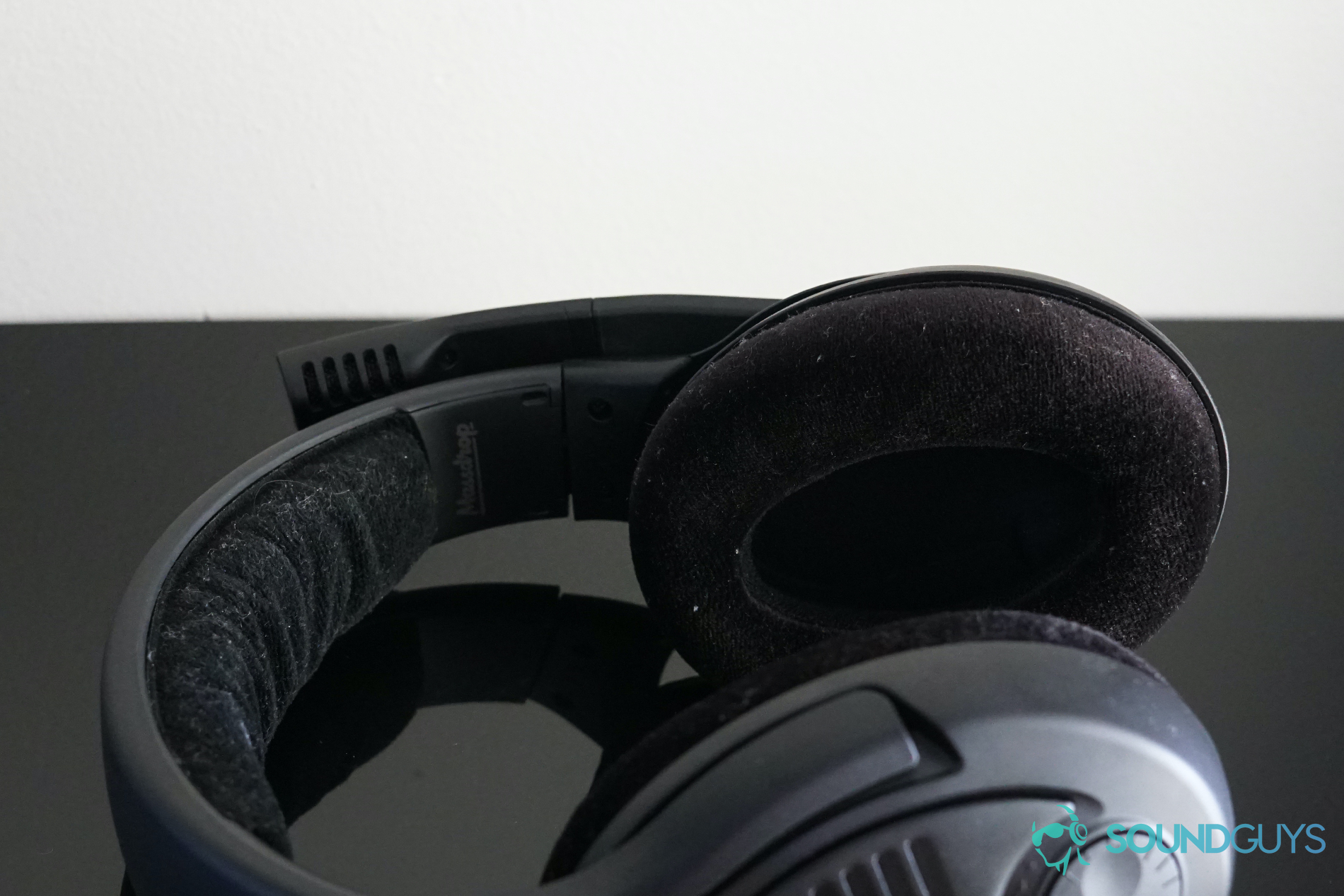 The Sennheiser PC37X lies on its side on a reflective black surface, with its microphone flipped up.