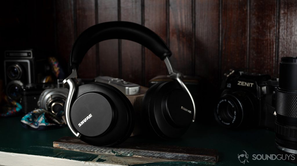 A picture of the Shure AONIC 50 noise canceling headphones surrounded by film cameras in a green and brown cabinet.