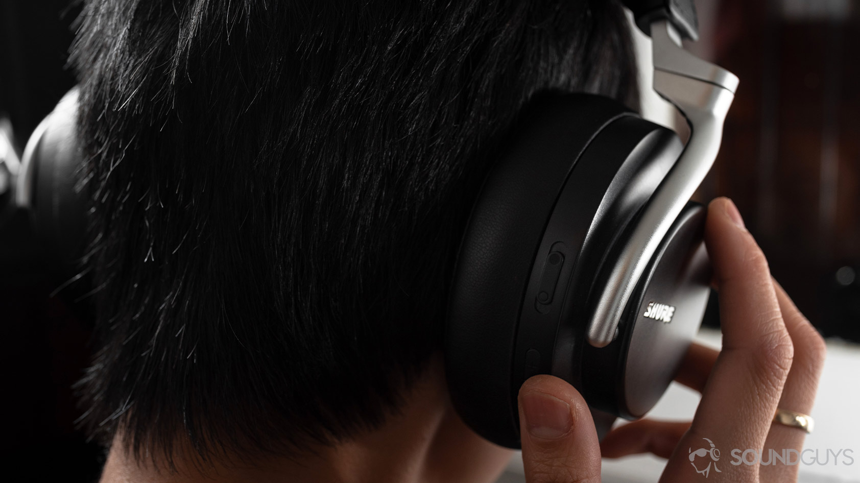 The Shure AONIC 50 noise canceling headphones' onboard controls used by a woman wearing the headset.