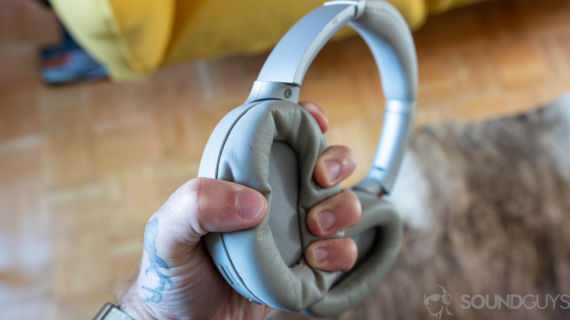 Man squeezing the plush memory foam earcups of the Sony WH-1000XM3