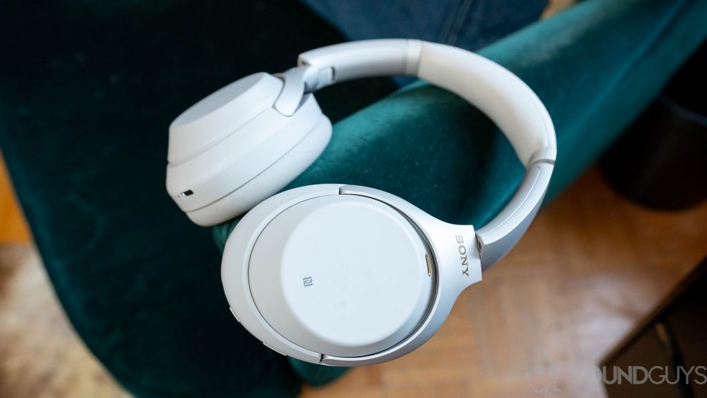 The Sony WH-1000XM3 headphones on green couch with NFC logo visible.