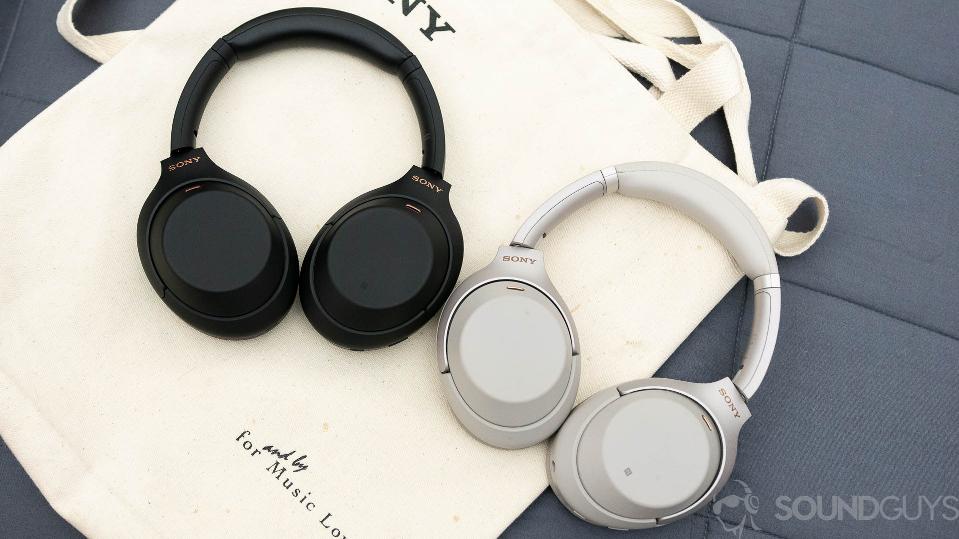 The Sony WH-1000XM4 and Sony WH-1000XM3 headphones sit on a canvas bag next to eachother.