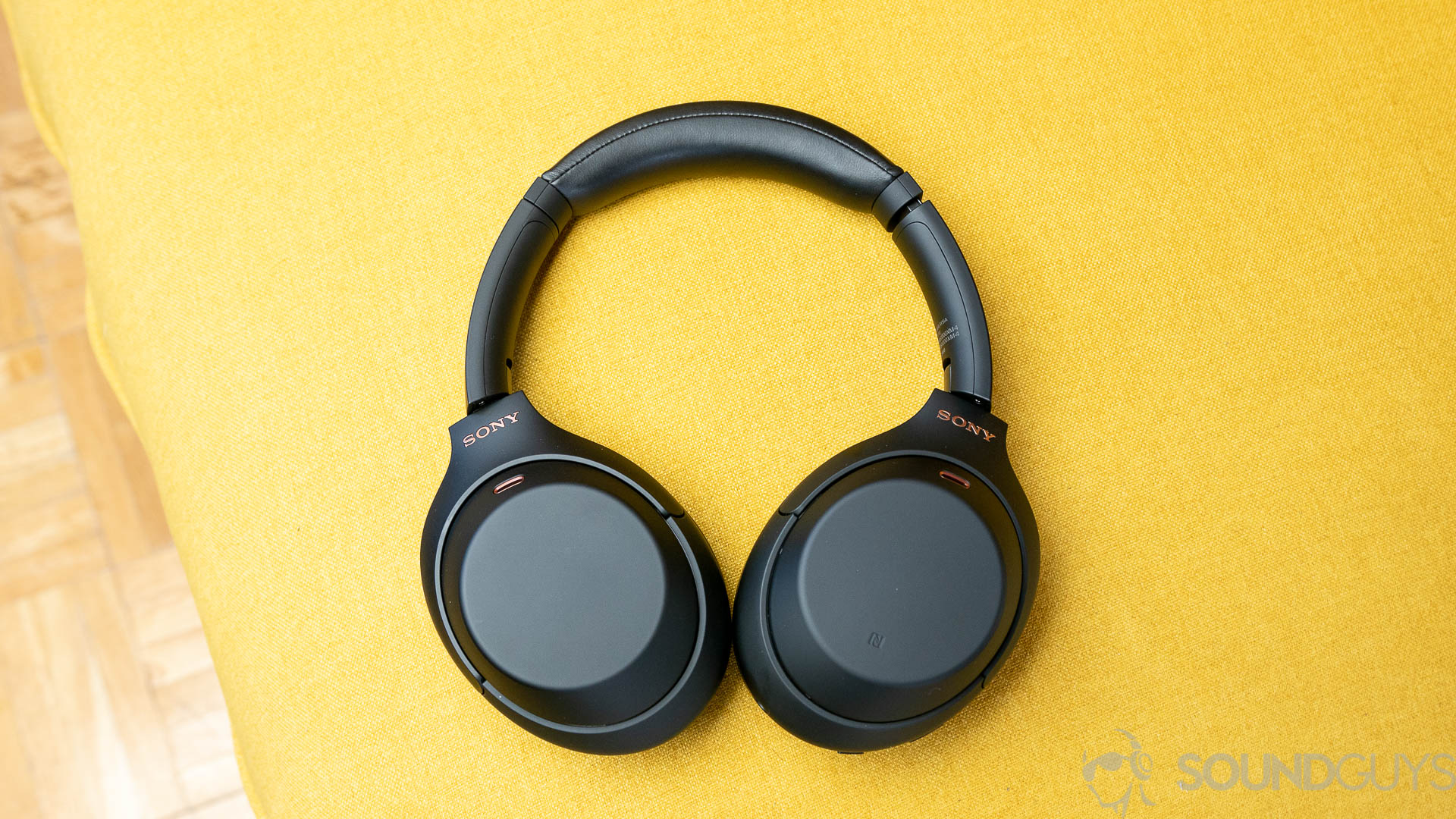 The Sony WH-1000XM4 headphones on a yellow couch.