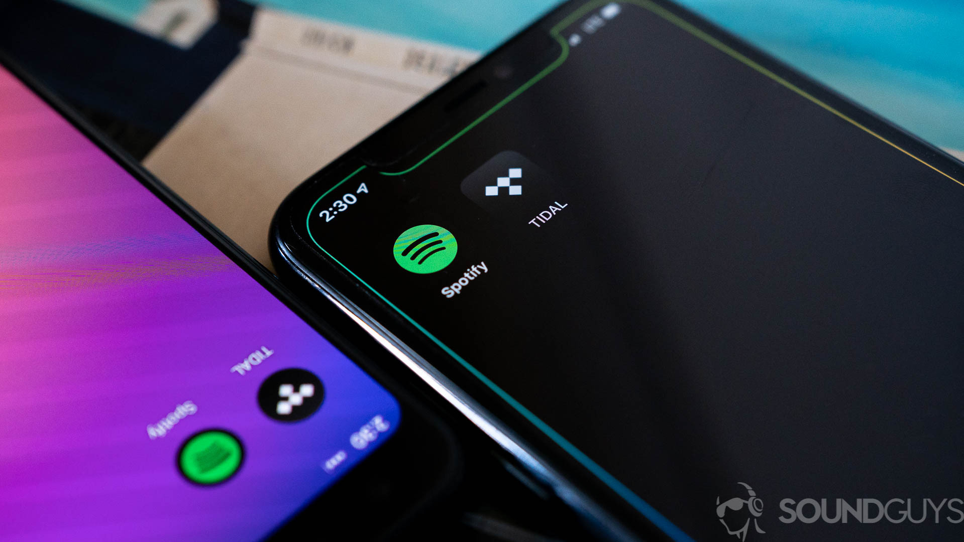 Spotify and Tidal's app icons on two smartphones