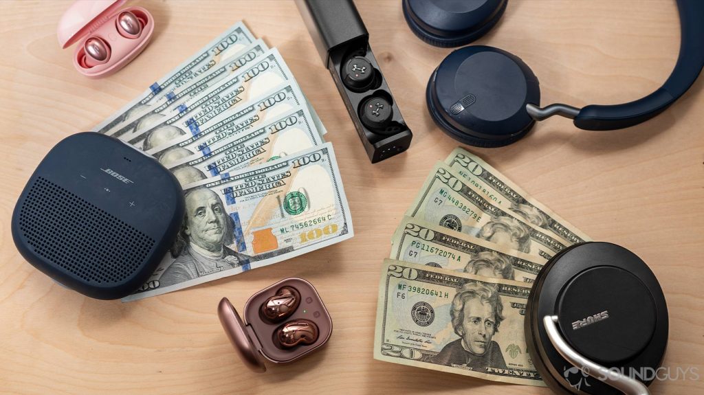 Money surrounded by wireless audio products like the Bose SoundLink Micro speaker, Samsung Galaxy Buds Live, 1More Colorbuds, Jabra Elite 45h, JBL True Wireless Flash X, and Shure AONIC 50.