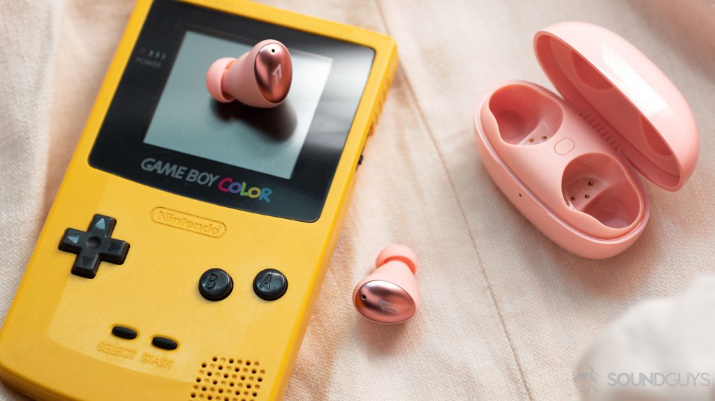 A picture of the 1MORE ColorBuds true wireless earbuds on top of a GameBoy, and the charging case is open to the left of the frame.