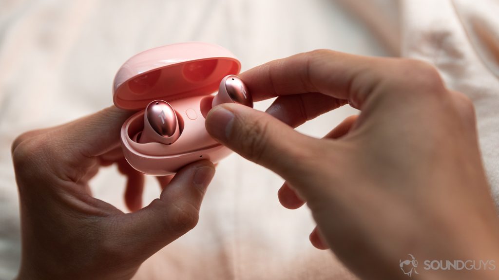The 1MORE ColorBuds true wireless earbuds case held by a woman as an earbud is removed.