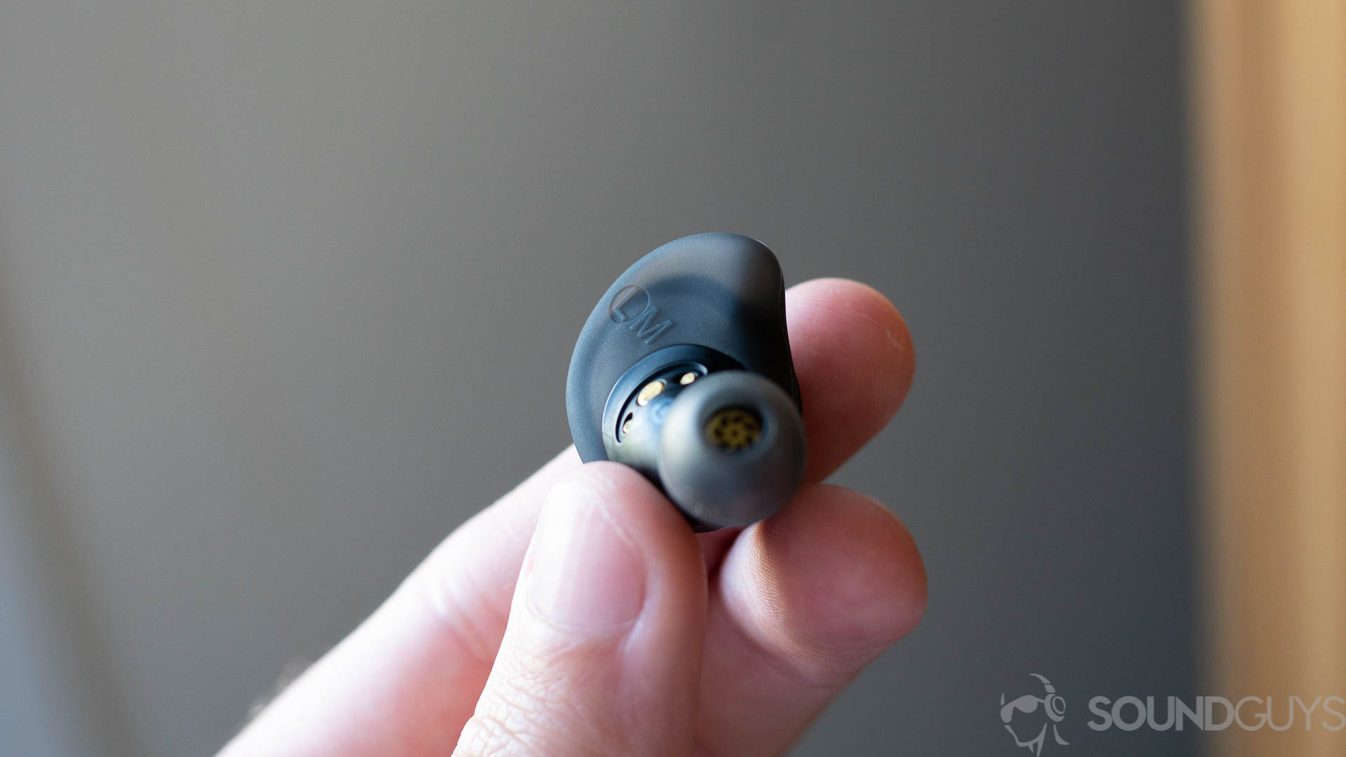 Man holding single Anker Soundcore Spirit Dot 2 earbud with focus on the AirWing stabilizer.