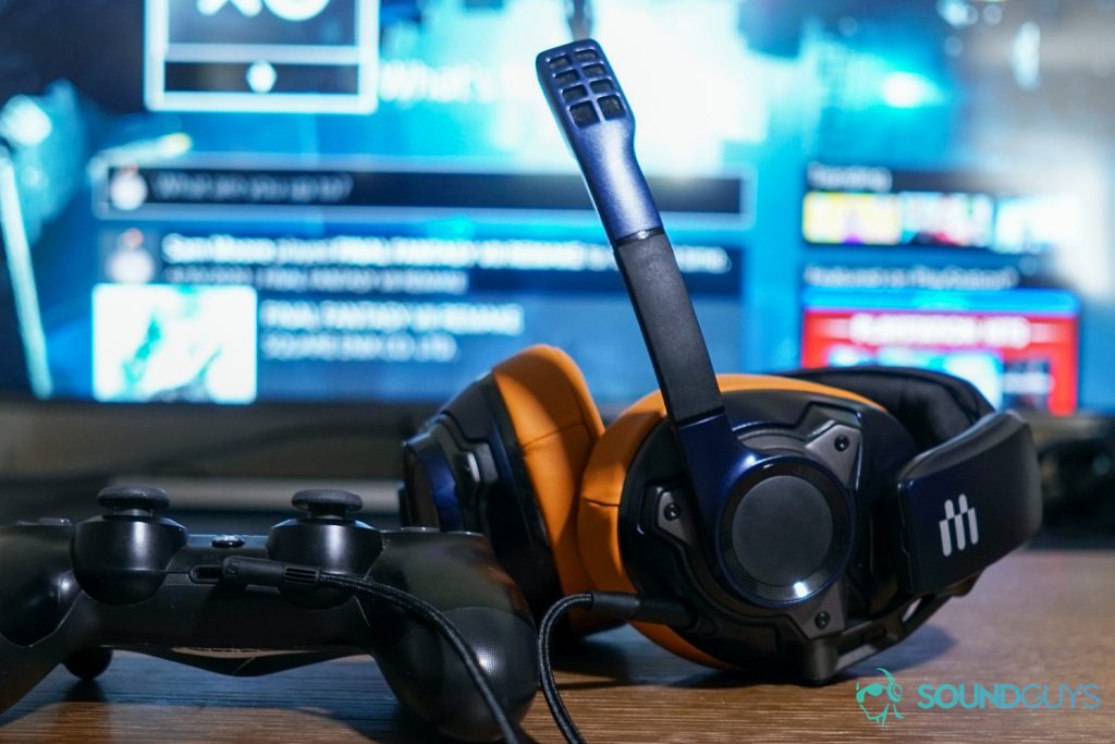 The EPOS Sennheiser GSP 602 gaming headset sits next a PlayStation DualShock 4 controller that it is plugged into, with a TV showing the PlayStation 4 dashboard in the background.