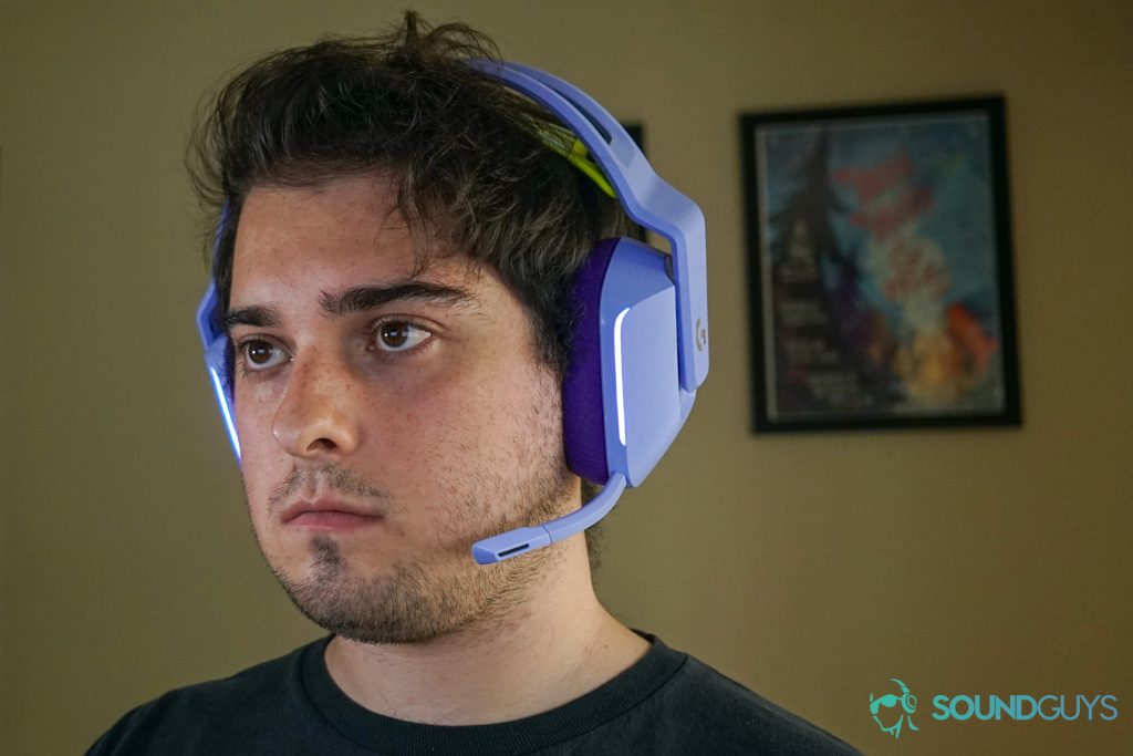 A man wears the Logitech G733 gaming headset with a poster for my brother my brother and me in the background.