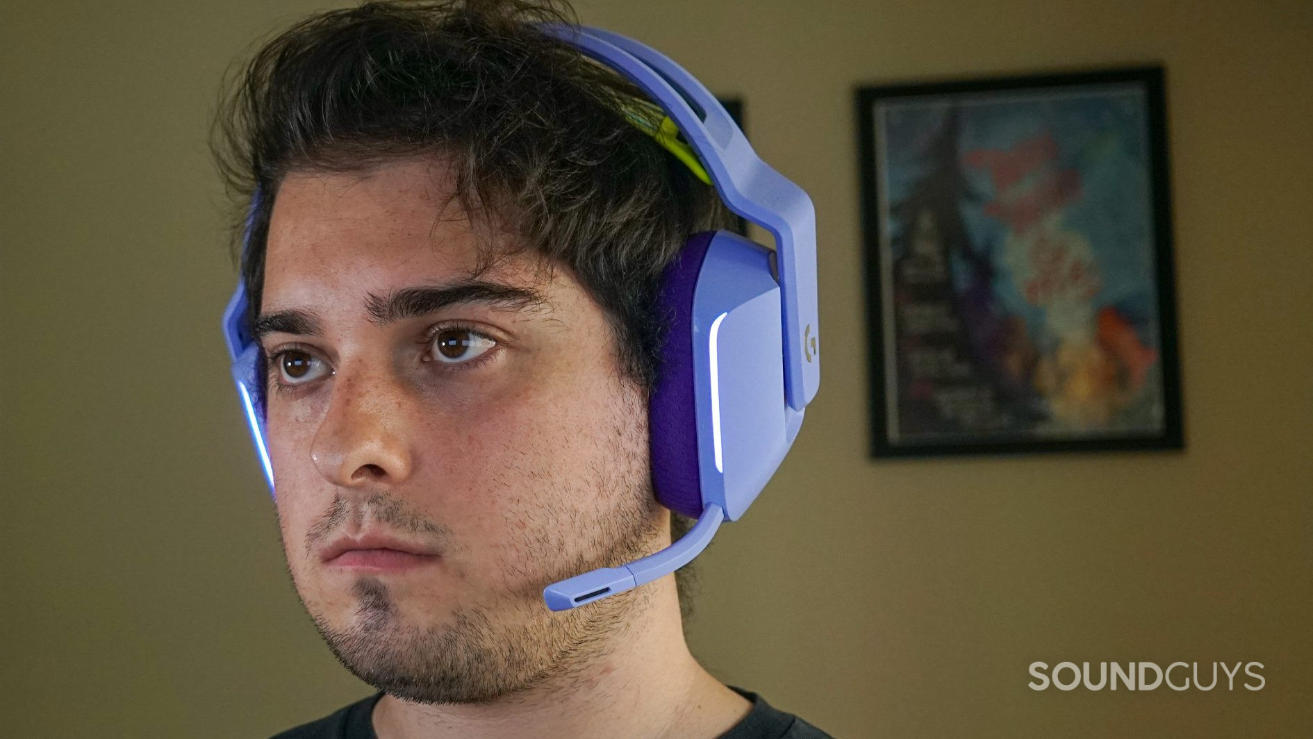 A man wears the Logitech G733 gaming headset with a poster for my brother my brother and me in the background.