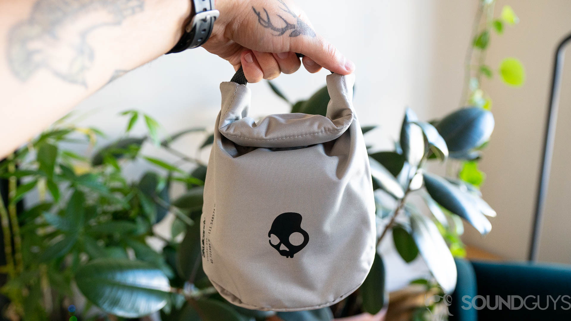 Man holding the Skullcandy Crusher Evo traveling pouch in front of plants.