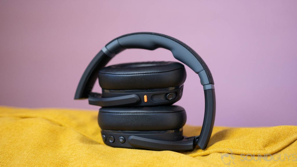 The Skullcandy Crusher Evo folded on top of yellow couch in front of purple wall.