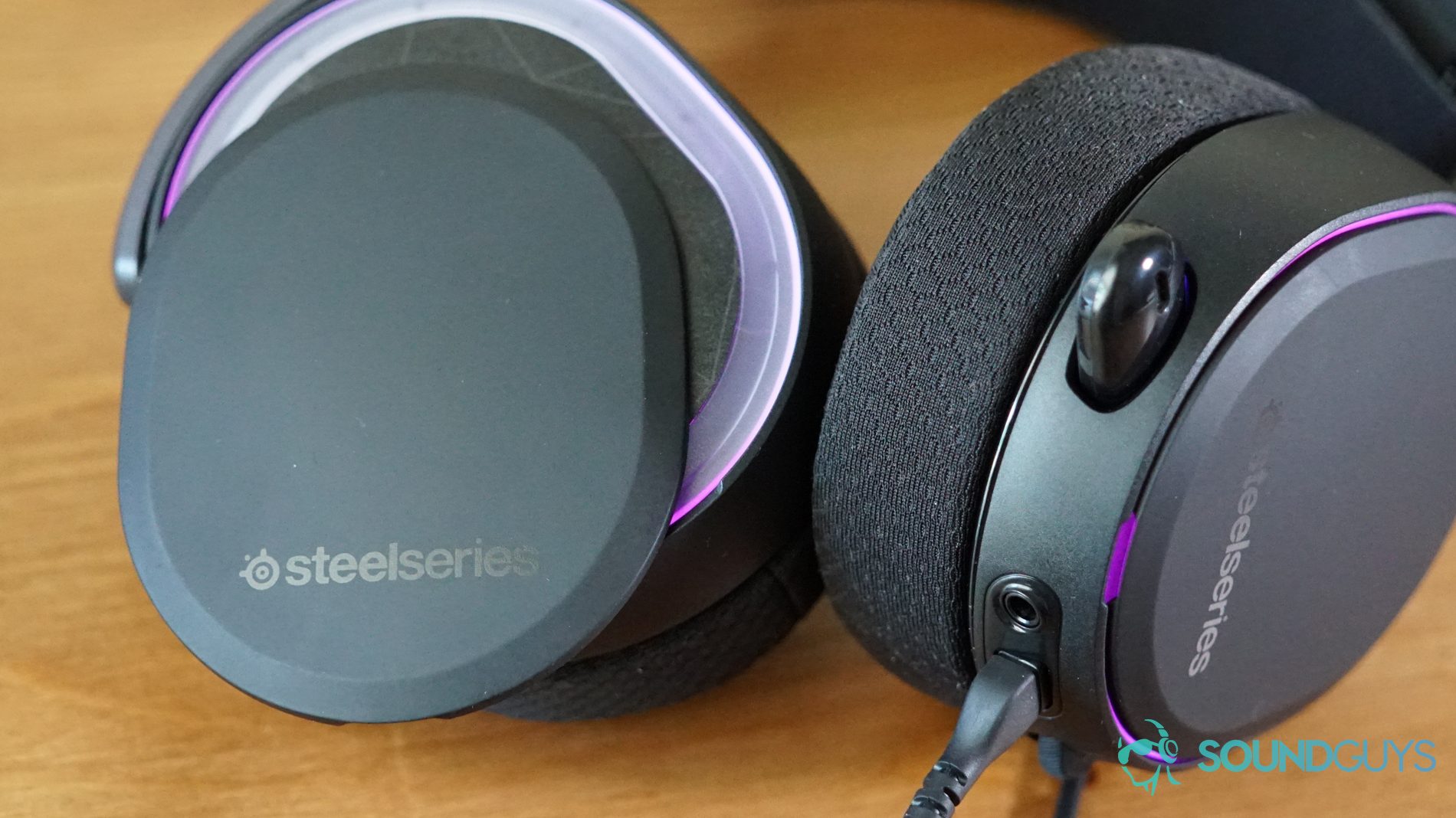 The SteelSeries Arctis Pro lays on a wooden table with its magnetic side plates detached.