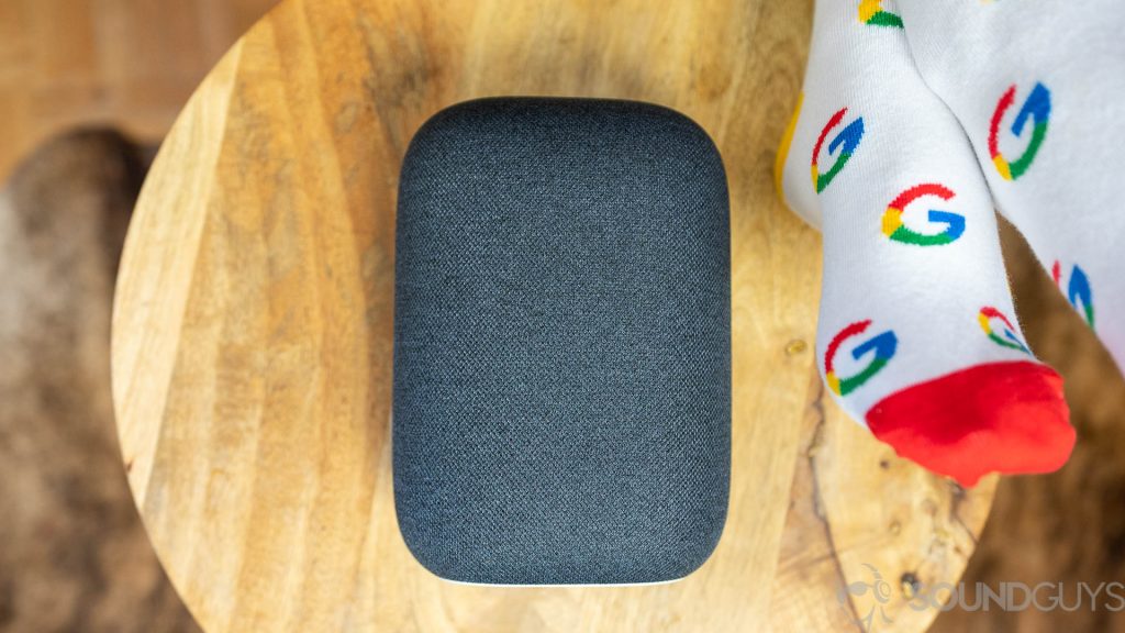 Google Nest Audio in black next to person wearing Google socks.