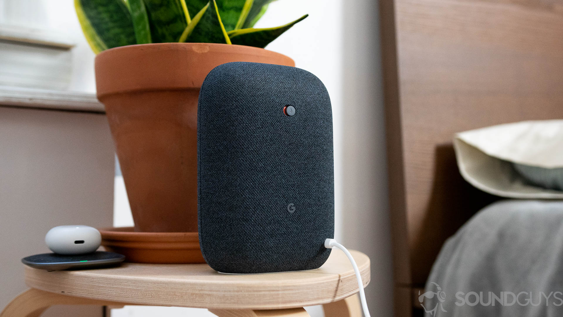 Google Nest Audio in black on nightstand next to bed