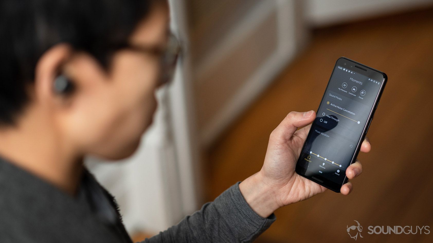 A woman uses the Jabra Sound+ app on a Google Pixel 3 while she wears the Jabra Elite 85t noise canceling true wireless earbuds.