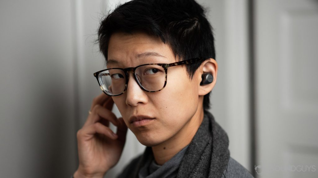 A woman wears the Jabra Elite 85t and operates the right earbud's control button.