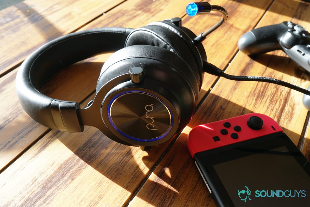 The Puro Sound Labs PuroGamer laying on a table in the sun next to a Playstation 4 Dual Shock controller and a Nintendo Switch