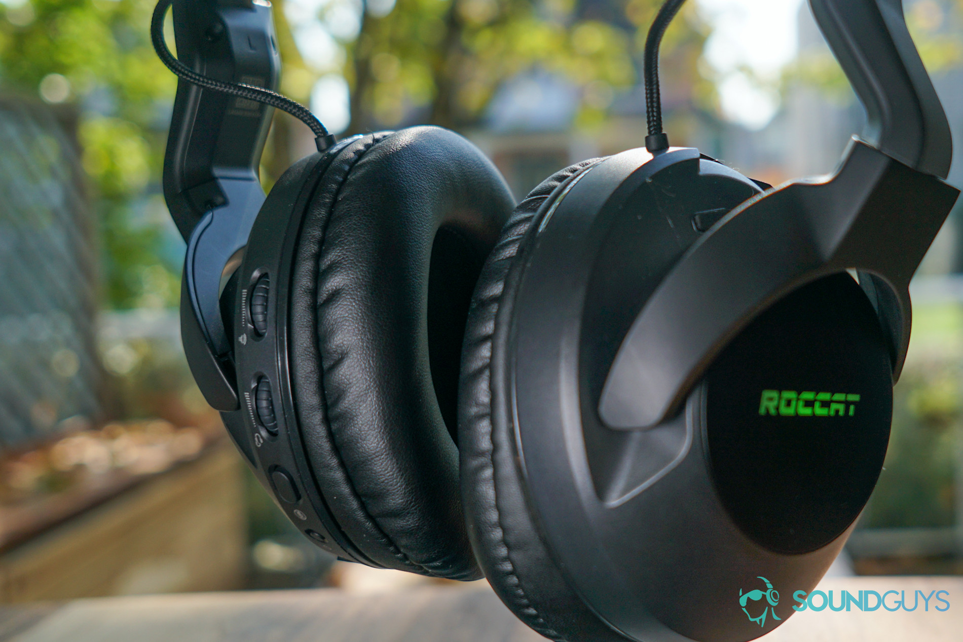 The Roccat Elo 7.1 Air hangs from a stand in front of a window, with it's on-ear controls in view.