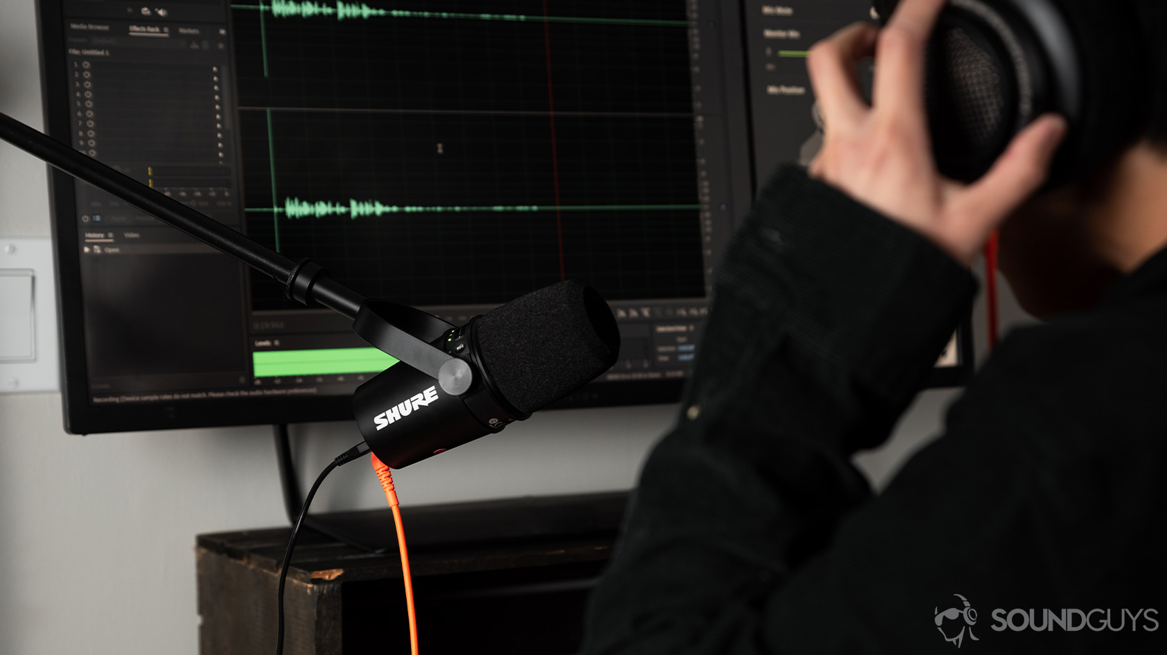 A person uses the Shure MV7 USB microphone and adjusts headphones as she monitors the recording.